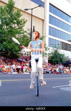 Un jongleur jongle tout en montant un monocycle alors que la foule regarde à Salt Lake City, Utah's Pioneer Day Parade annuelle. Banque D'Images