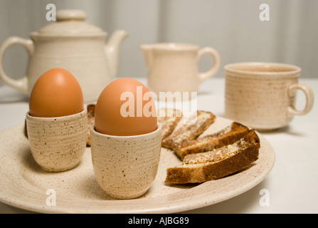 Œufs durs dans les tasses avec des soldats et un toast beurré théière tasse et pot à lait Banque D'Images