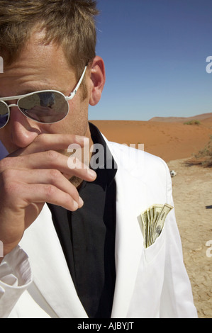 Homme dans un costume blanc avec de l'argent dans sa poche, dans le désert Banque D'Images