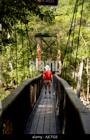 Parc d'État de Floride randonnée femme OLeno randonneur avec chemise rouge traversant le pont suspendu en bois Banque D'Images