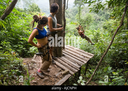 Les touristes espagnols la tyrolienne de maison de l'arbre d'une plate-forme d'atterrissage à l'expérience Gibbon près de Huay Xai sur Mékong au Laos Banque D'Images