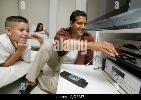 Père Fils mettait avec disque dans un lecteur DVD dans la salle de séjour Banque D'Images