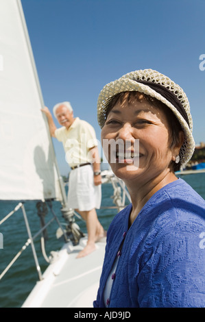 Woman smiling on voilier, mari en arrière-plan, (portrait) Banque D'Images