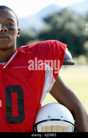 Football Player holding helmet sur champ, cropped Banque D'Images