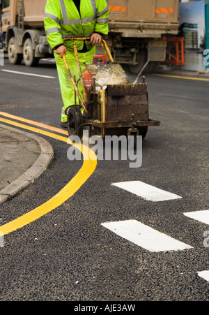 Marquage routier, piste de route, garder à l'écart, Santé et sécurité, peinture de route, Hommes au travail, peinture pour chariot, marqueur de ligne, suivant la ligne de trottoir, repère jaune. Banque D'Images