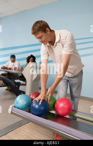 Jeune homme au bowling ball choix Banque D'Images