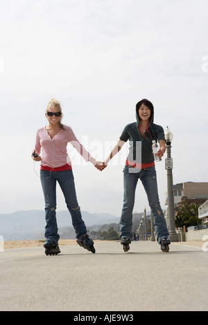 Deux femmes sur rollers holding hands on street Banque D'Images