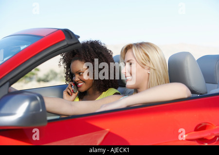 Deux jeunes femmes driving red cabriolet Banque D'Images