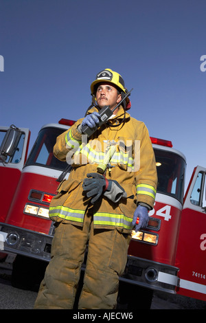 Fire fighter aide radio à deux voies en face d'incendie moteur, low angle view Banque D'Images