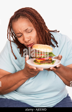 L'excès de Woman holding hamburger Banque D'Images