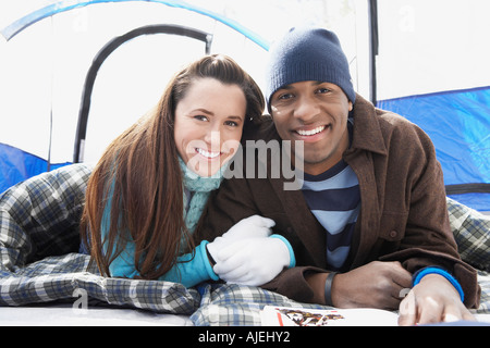 Jeune couple couché dans des sacs de couchage en tente, portrait. Banque D'Images