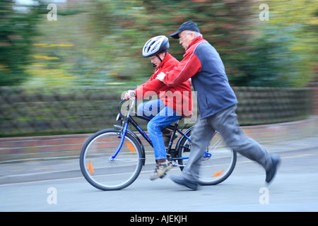 Un grand-père pousse son petit-fils sur un vélo Banque D'Images