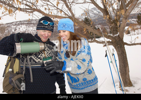 Couple drinking out de champ couvert de neige en thermos Banque D'Images