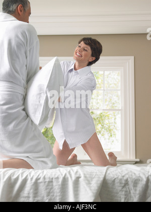 Couple having pillow fight on bed Banque D'Images