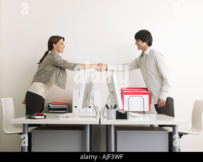 L'homme et la femme se serrer la main au-dessus d'un bureau, vue latérale Banque D'Images