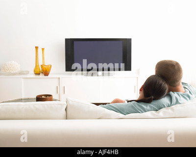 Vue arrière du couple on sofa watching TV Banque D'Images