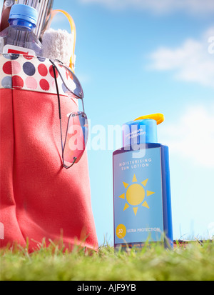 Bouteille de lait solaire et sac avec articles de plage dans la région de grass, close-up Banque D'Images