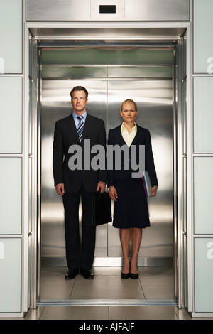 Businesspeople côte à côte dans l'ascenseur, vue de face, portrait Banque D'Images
