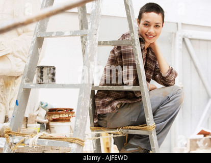 Décorateur d'intérieur femme assis sur l'échelle au lieu de travail, portrait Banque D'Images