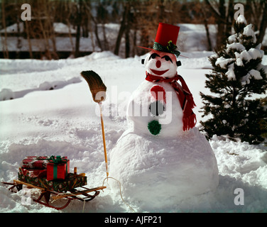 Le Snowman holding a broom à traineau empilé avec des paquets de vacances de Noël gaiement enveloppés Banque D'Images