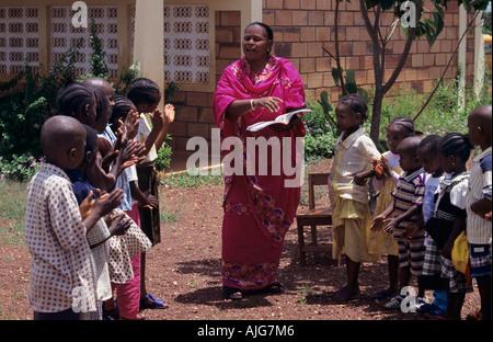 Enseignant de l'école avec les enfants de l'école primaire en leçon de chant en dehors de la classe, en Guinée, en Afrique de l'Ouest Banque D'Images