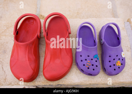 Paire de sandales adult croc rouge et violet sandales enfant sur l'étape devant la porte UK Banque D'Images