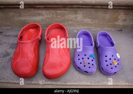 Paire de sandales adult croc rouge et violet sandales enfant porte sur UK Banque D'Images