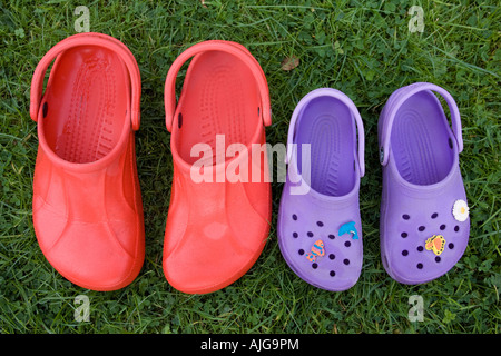 Paire de sandales adult croc rouge et violet sandales enfant sur l'herbe Banque D'Images