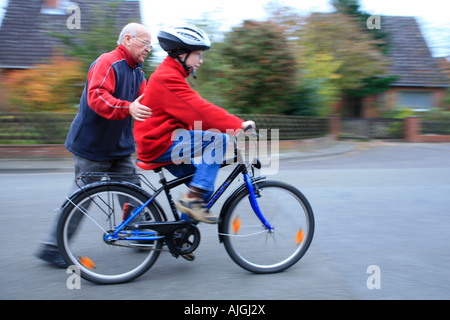 Un grand-père pousse son petit-fils sur un vélo Banque D'Images