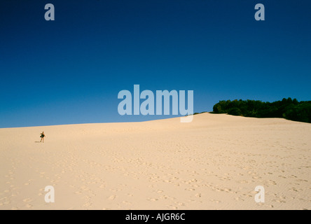 Une femme solitaire marchant sur une grande dune de sable sur Fraser Island, en Australie. Banque D'Images