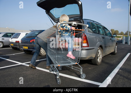 Photo d'une maman et sa fille âgée de deux ans, le chargement de l'achats hebdomadaires dans la voiture Banque D'Images