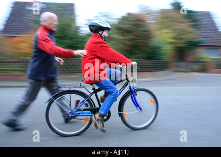 Un grand-père pousse son petit-fils sur un vélo Banque D'Images