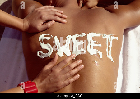 Woman applying sun cream on man's back Banque D'Images