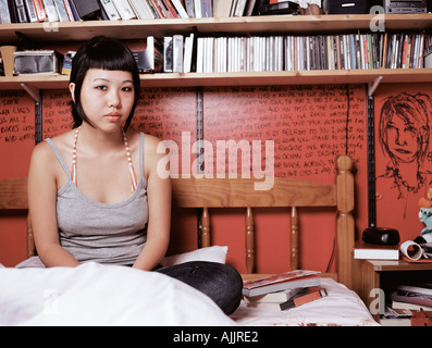 Teenage girl sitting on bed Banque D'Images