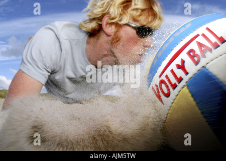 Jeune homme blond à jouer au volleyball de plage Banque D'Images