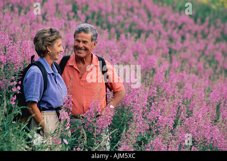 Senior couple randonnées dans le champ de fleurs violettes Banque D'Images
