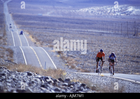 Un couple à vélo sur une route du désert près de Big Pine CA Banque D'Images