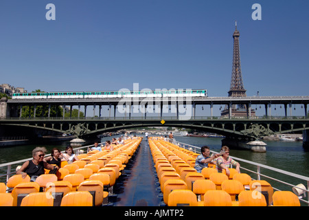 Vue sur le pont supérieur et les passagers sur un "bateau-mouche" Bateau de tourisme qui passe sous un pont de métro à Paris. Banque D'Images