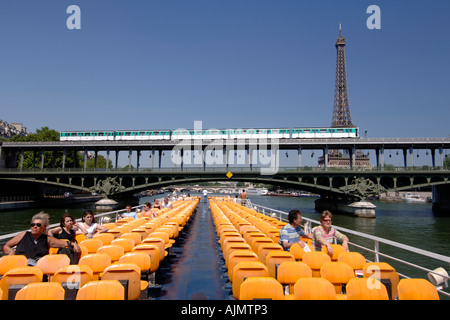 Vue sur le pont supérieur et les passagers sur un bateau-mouche Bateau de tourisme qui passe sous un pont de métro à Paris. Banque D'Images