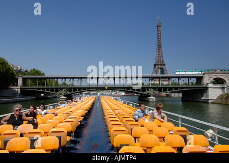 Vue sur le pont supérieur et les passagers sur un bateau-mouche Bateau de tourisme qui passe sous un pont de métro à Paris. Banque D'Images