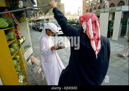 Dubaï ÉMIRATS ARABES reading magazine on street Banque D'Images