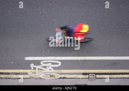 Royal Mail postman symbole cycliste en route avec cycliste passant à la vitesse Banque D'Images