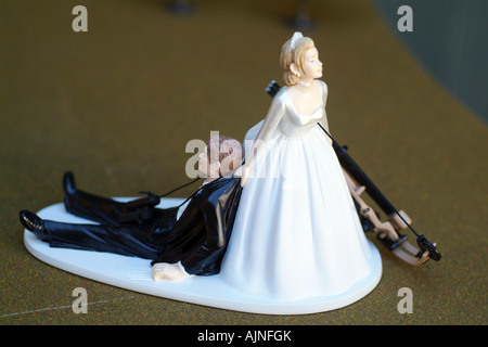 Un petit gâteau en plastique topper avec bride en faisant glisser le marié. Promise a un arc de chasse. L'humour de mariage. Banque D'Images