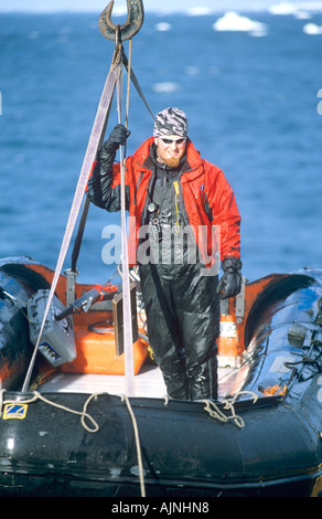 Grue levage à bord d'un zodiac de la mer, avec l'homme continu à bord de l'Antarctique Banque D'Images