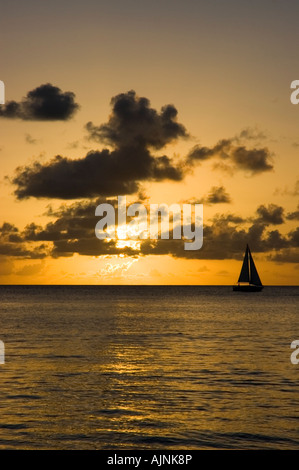 Voilier silhouette sur le coucher de soleil au large de l'île antillaise de la Barbade Banque D'Images