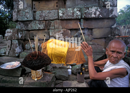 Personnes âgées nun priant avec de l'encens à un culte à l'intérieur des murs de l'Angkor Thom Angkor Cambodge Banque D'Images