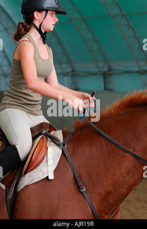 Cantoring adolescente sur un cheval de race Thoroughbred de la baie intérieure au cours d'équitation Banque D'Images