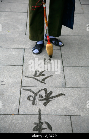 Calligraphie un homme écrit sur le sol avec de l'eau au pinceau Le Parc Beihai Beijing Chine Banque D'Images