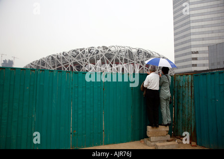 Les gens à la recherche sur le site de construction du stade olympique, aussi connu comme le nid Beijing Chine Banque D'Images