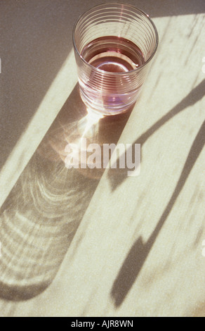 Dans l'Ombre lumière chaude sur la surface pâle de verre de verre rose ou de rince-bouche avec deux brosses à dents et rideau Banque D'Images